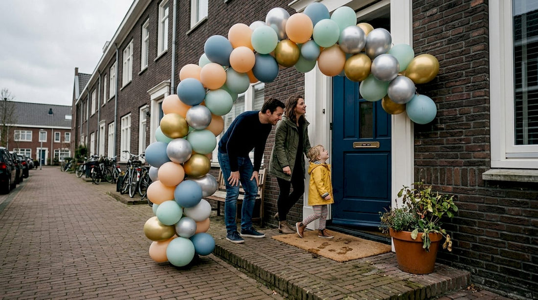 Een gezin loopt vrolijk hun huis binnen via een kleurrijke ballonnenboog.