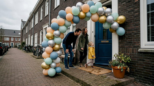 Een gezin loopt vrolijk hun huis binnen via een kleurrijke ballonnenboog.