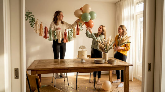 Een groepje jonge vrouwen is druk in de weer met het versieren van de woonkamer voor een gezellige babyshower.